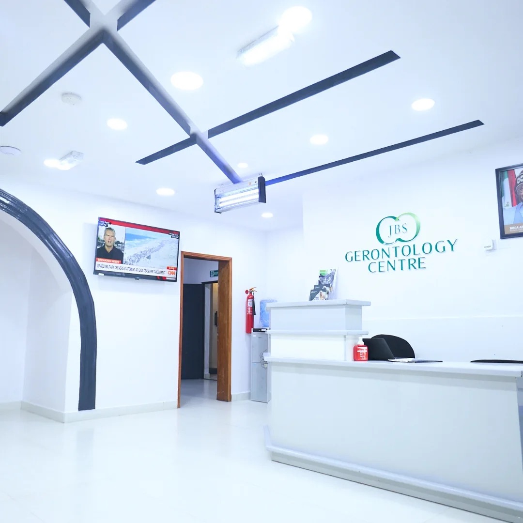 The JBS Gerontology Centre reception desk with the centre's logo on the wall